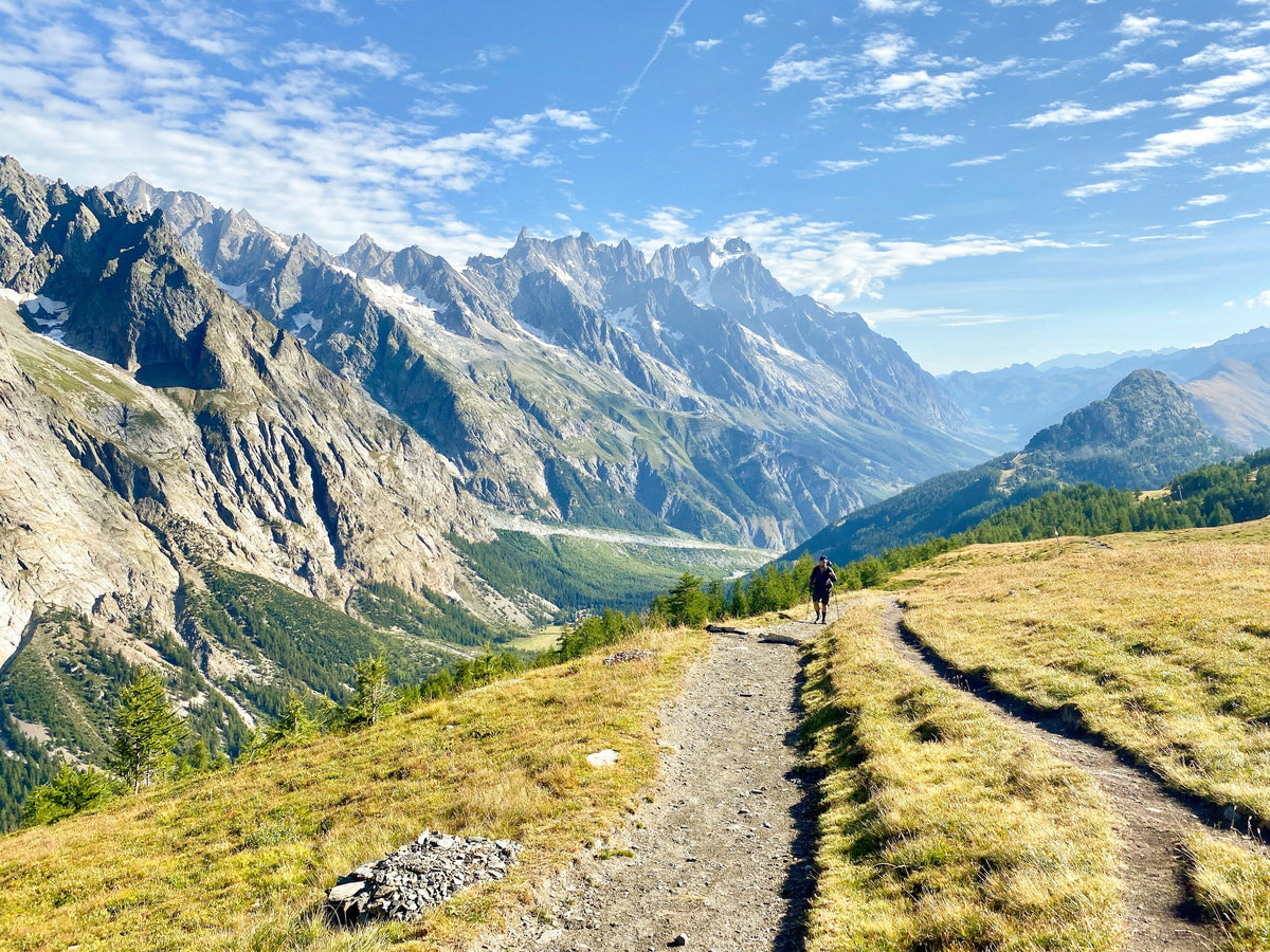 Hiker on a trail facing the Mont Blanc massif