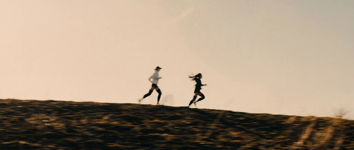 Two runners on a hill at sunset